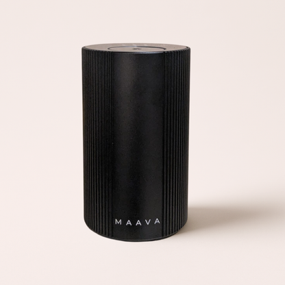A black cylindrical portable speaker with vertical ridges and the brand name 'MAAVA' printed in white near the bottom, set against a solid light beige background.